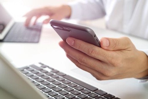 Hand mit Handy und Laptop