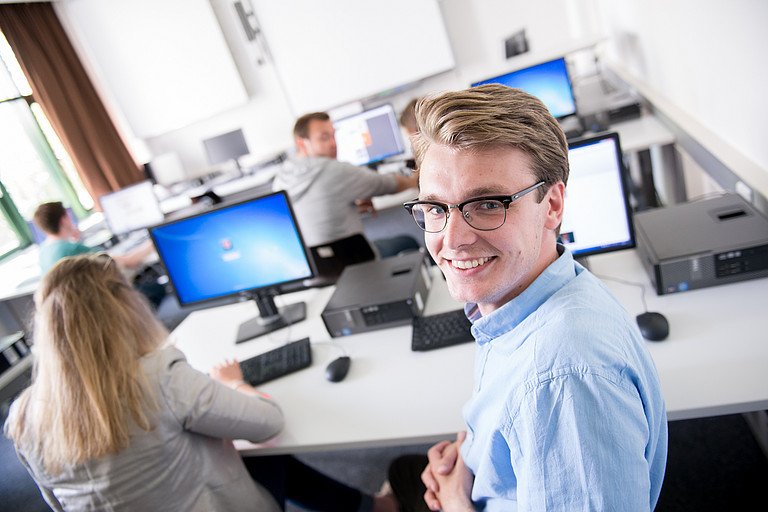 Symbolbild Junger Mann vor Computern